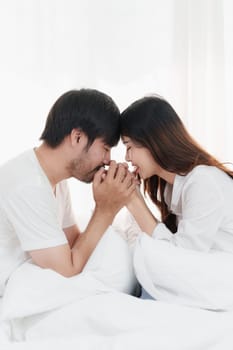 Beautiful asian couple in love and smiling sitting on bed. Romantic moment, relationships, family concept