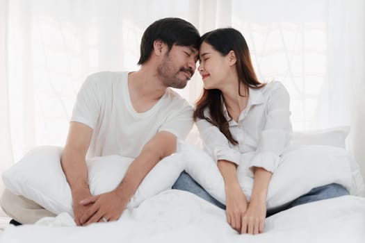 Beautiful asian couple in love and smiling sitting on bed. Romantic moment, relationships, family concept