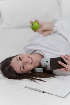 Portrait of Good Healthy woman eating green apple and resting in bed at bedroom. Lifestyle at home concept