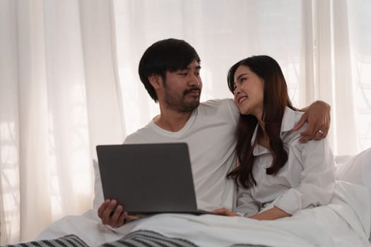 Beautiful asian couple in love and smiling sitting on bed. Romantic moment, relationships, family concept