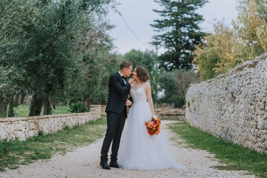 Happy stylish smiling couple walking in Tuscany, Italy on their wedding day. The bride and groom walk down the street by the hands. A stylish young couple walks. Husband and wife communicate nicely. Lovers run through the streets of the city.