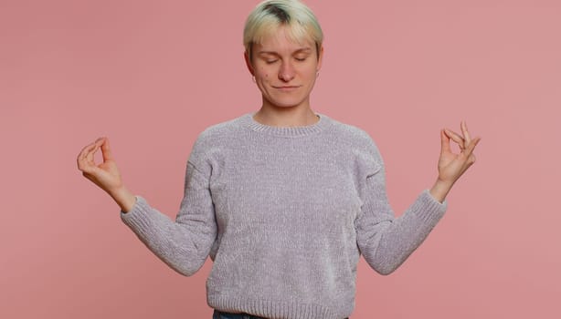 Keep calm down, relax, inner balance. Woman with short hair breathes deeply with mudra gesture, eyes closed, meditating with concentrated thoughts, peaceful mind on pink background. Lgbt gay lesbian