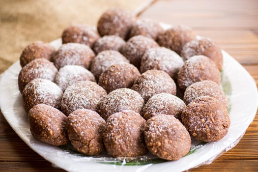 chocolate sweet cakes from mashed biscuits with additives, in a plate on a wooden table.