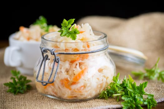Sauerkraut with carrots and spices in a bowl on a wooden table.