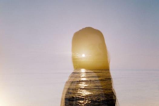 Sun on the horizon through the silhouette of a girl with long hair. High quality photo