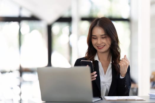 Successful and exciting businesswoman Young woman excited to win on her smartphone at work.