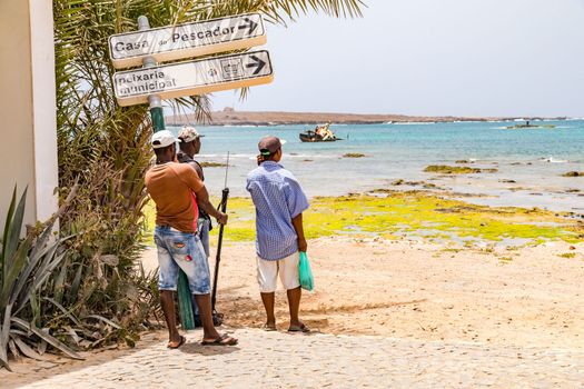Three men at the harbor of Sal Rei look at the Atlantic Ocean, Boa Vista, Cape Verde Islands