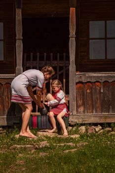 mother and daughter in Ukrainian folk dresses on the threshold of the house.