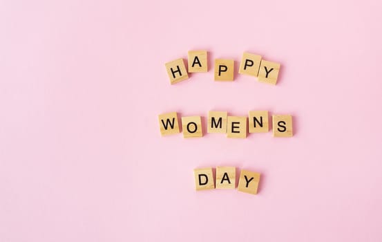 March 8, postcard. Text sign from wooden letters Happy Women's Day on a pink background. Stylish flat lay, greeting card