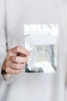 A young woman is holding a transparent plastic bag with a zipper in her hands for storing transparent braces or aligners. Close-up of new name packaging.