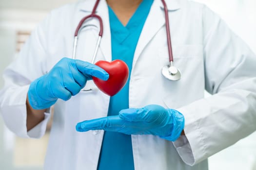 Doctor holding a red heart in hospital ward, healthy strong medical concept.