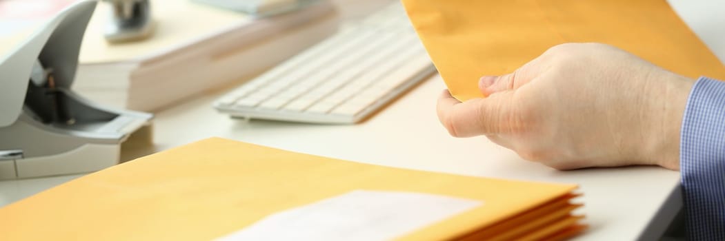 Businessman takes out documents from yellow envelope. Corporate business mail concept