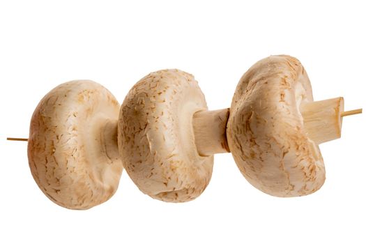 fresh mushrooms are strung on a wooden skewer isolated on a white background. close-up. Products for the kitchen.