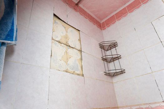 an old dirty shabby bathroom with fallen tiles.an old shelf. a piece of peeling wall. repair. a scratched bathtub. removal