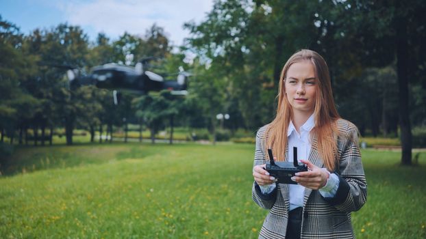 A cute girl controls a drone in the park