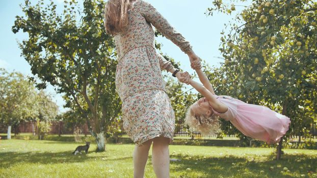 A mother circles her daughter in the garden outside the house