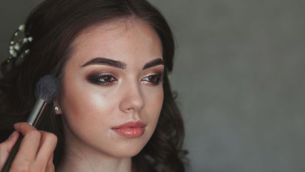 Girl make-up artist applies powder on the face of the model