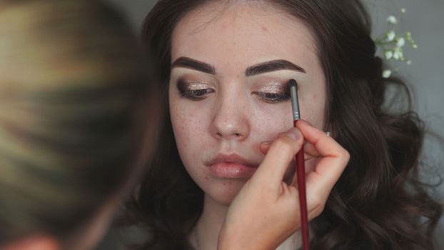 Makeup artist paints the eyelids of a girl model