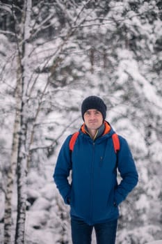 Man in winter jacket walking in snowy winter forest, snowy winter day