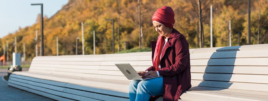 Arab woman freelancer working on laptop at public park, copy space. Muslim female browsing social networks and her blog - blogger and influencer