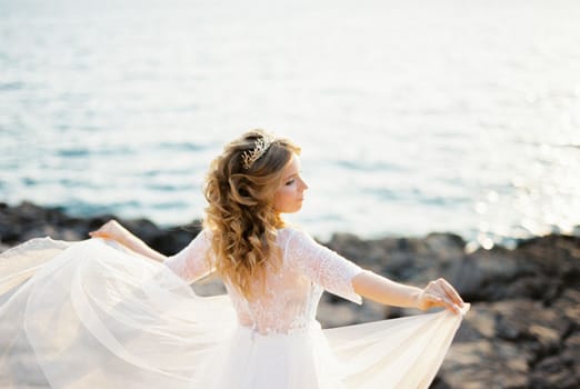 Bride stands with her arms outstretched with the overskirts of her dress. High quality photo