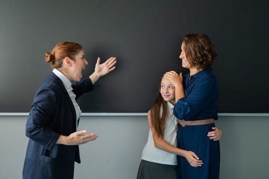 The teacher screams at the schoolgirl and her mother standing at the blackboard