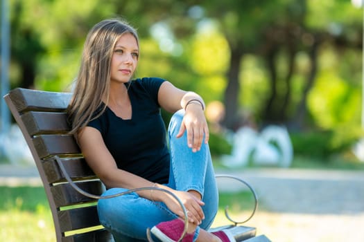 Girl sitting on a bench in the park, close up