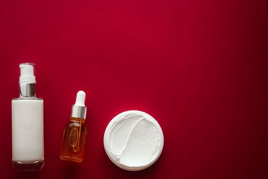 Skincare cosmetics and anti-aging beauty products, luxury skin care bottles, oil, serum and face cream on red background.