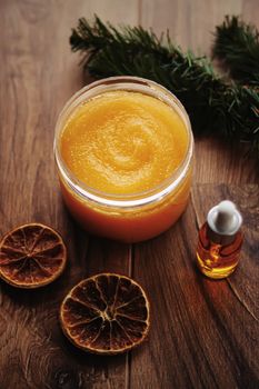 Citrus and honey orange body scrub jar on rustic wood background, beauty cosmetic and skincare product.