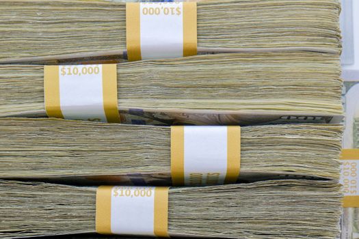 Close up of 4 straps of 100 dollar bills totaling ten thousand US dollars each stacked on top of each other, side view. High quality photo