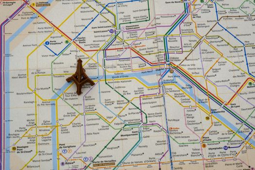 Close up top view of toy Eiffel tower on Paris subway map showing metro lines, stations. High quality photo