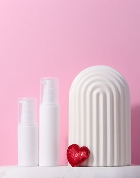 A white plastic tub with a dispenser stands on a marble stand and a ceramic decorative arch, cosmetic container