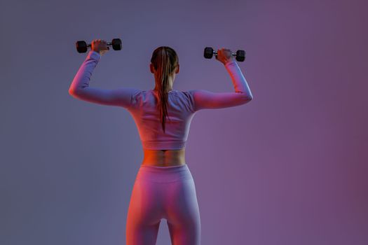 Woman doing exercises with dumbbells on studio background . Sport and healthy lifestyle