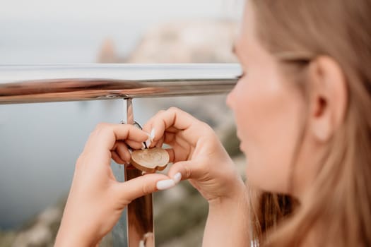 Hand, lock, heart, love, valentines day. Close up view of a woman holding a heart shaped lock that is locked onto a chain link fence.