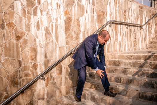 Portrait of a senior professional man in a suit with various problems. A middle-aged businessman with a briefcase descends the stairs.