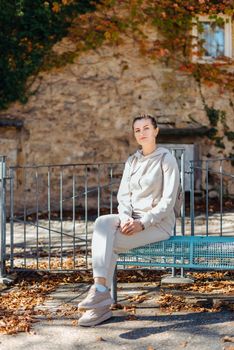 Attractive young woman sitting on a bench enjoying a view of medieval town in Europe. Summer holidays concept.