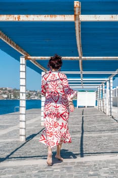 woman in a hat and dress enjoys the blue sea and summer. Welcome summer