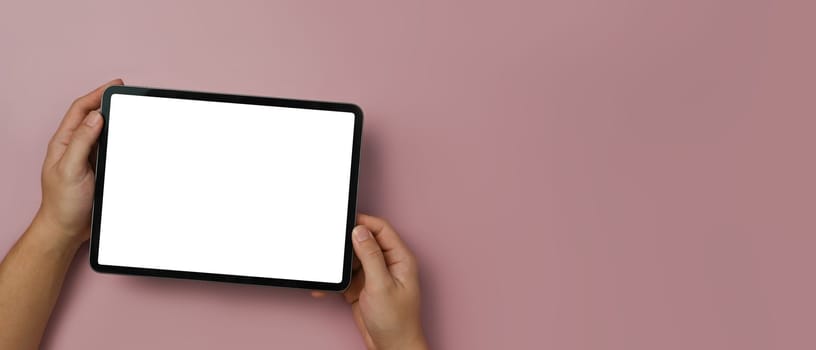 Above view of man hands holding digital tablet with empty display over pink background. Copy space for your text.