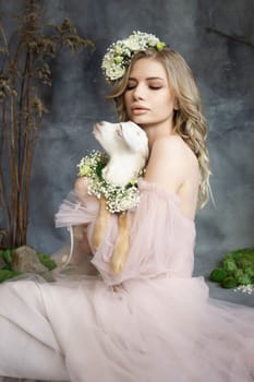 A young blonde woman in an airy pink dress with a white kid. Spring portrait of a woman