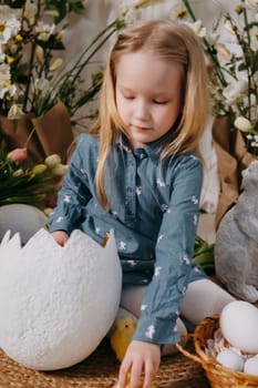 Two girls in a beautiful Easter photo zone with flowers, eggs, chickens and Easter bunnies. Happy Easter holiday