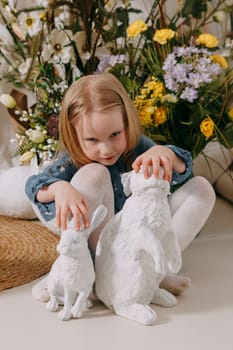 Two girls in a beautiful Easter photo zone with flowers, eggs, chickens and Easter bunnies. Happy Easter holiday