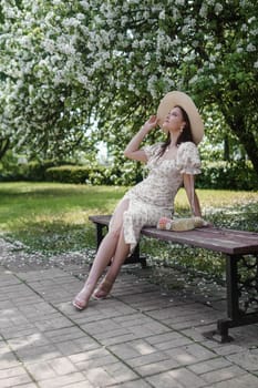 An attractive long-haired woman walks in the spring in the park of blooming apple trees. Spring portrait of a woman