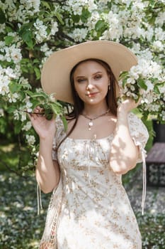 An attractive long-haired woman walks in the spring in the park of blooming apple trees. Spring portrait of a woman