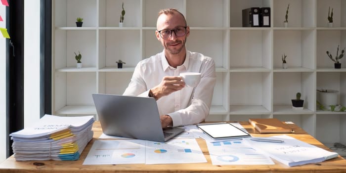 Businessman drinking coffee and working in office.