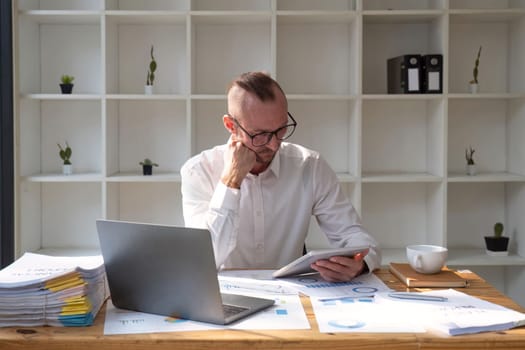 Young Businessman Using Digital Tablet At Workplace In Office, Browsing New Application Or Social Media.