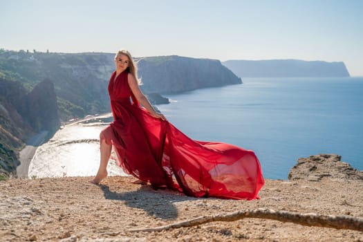 A woman in a red flying dress fluttering in the wind, against the backdrop of the sea