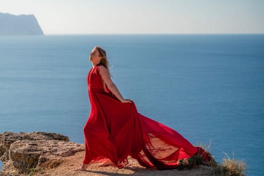 A woman in a red flying dress fluttering in the wind, against the backdrop of the sea