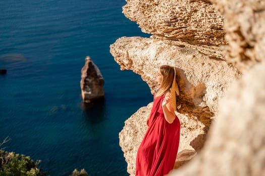 A woman in a red flying dress fluttering in the wind, against the backdrop of the sea