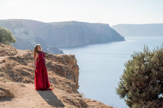 A woman in a red flying dress fluttering in the wind, against the backdrop of the sea