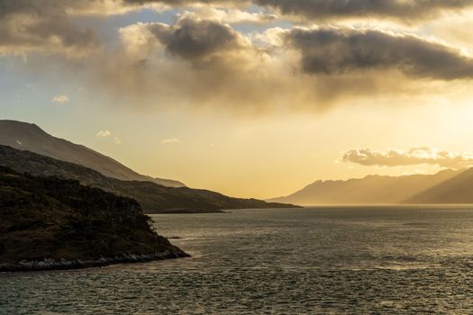 Cruise ship sailing between mountains in Glacier Alley of Beagle channel in Chile at sunrise